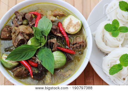 Thai-rice-flour noodles (kanom Jeen) arranged with green curry on brown wood floor