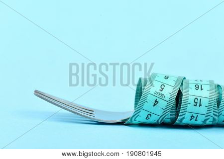 Fork And Measuring Tape Tied Around It, Isolated On Turquoise