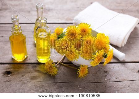 Fresh yellow flowers tussilago in mortar on wooden background. Wellness setting. Selective focus.
