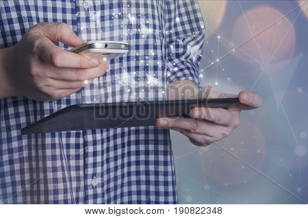 Man using smart phone and tablet pc with futuristic interface. Global network connection social networking or synchronization concept.
