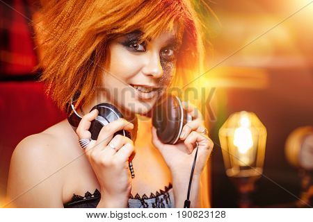 Redhaired girl in headphones with unusual makeup at the disco