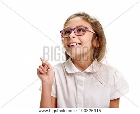 Young smiling genious schoolgirl in glasses pointing up