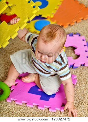 Child jigsaw develops children. Family puzzle making baby. Portrait of boy top view. Playing on floor in kindergarten. Kid learns to count and study of figures when playing.