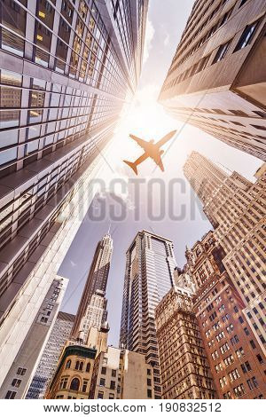 plane flying over highrise skyskrapers in the sun, Manhattan financial district, New York City