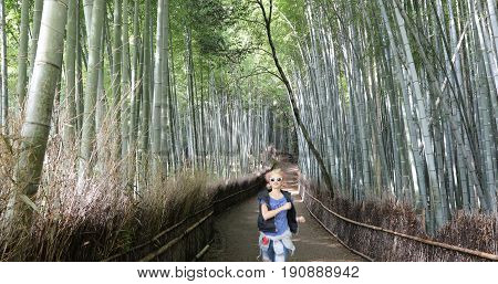 Happy tourist woman running in bamboo forest at Sagano in Arashiyama, Kyoto, Japan. Travel asia concept. Freedom and enjoying concept. Kyoto's popular landmark and touristic destination.