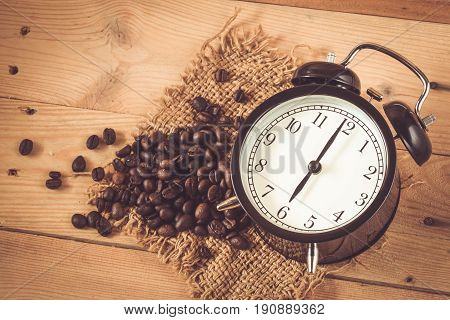 6 O'clock Retro Clock With Arabica Coffee Bean On Sack And Wood Background Table.