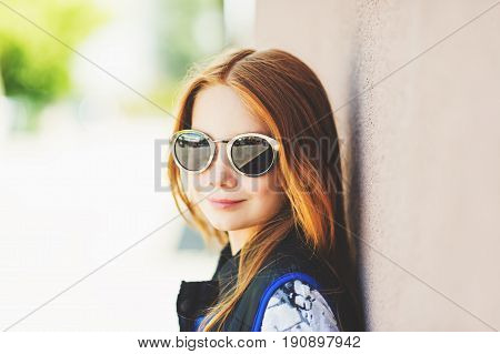 Outdoor close up portrait of adorable red-haired girl