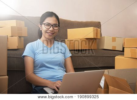 Successful cheerful small business owner smiling. Portrait of Young Asian woman with a laptop in her small warehouse.