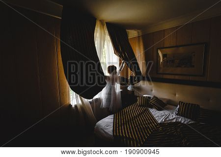 bride is looking through the window in hotel