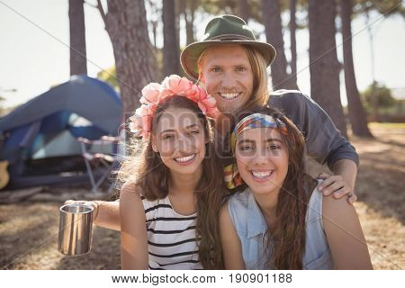 Portrait of smiling friends against tent camping at forest on sunny day