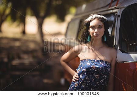 Portrait of young woman standing by motor home at forest