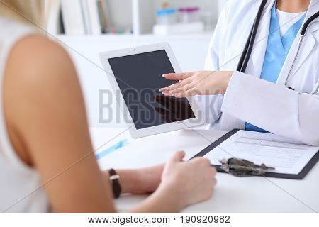 Close up of a doctor and  patient hands while phisician pointing into tablet computer monitor. Medicine and health care concept