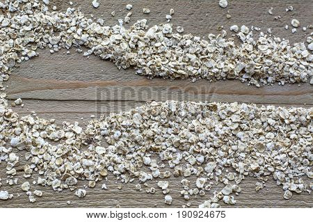 Many brown raw cereals in form of spoon are on the wooden background