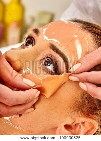 Collagen face mask. Facial skin treatment. Woman receiving cosmetic procedure in beauty salon. Bottle with moisturizing cream on background. Cropped shot of removing wrinkles.