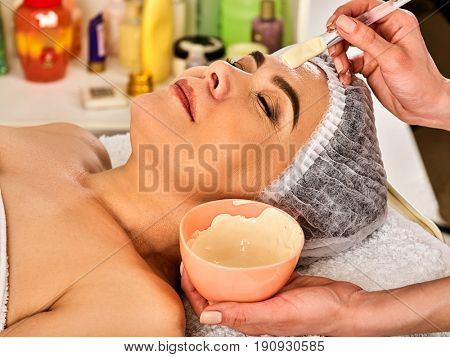 Collagen facial mask for skin treatment. Face of woman of elderly woman 50-60 years old receiving cosmetic procedure in beauty salon close up . Professional beautician.