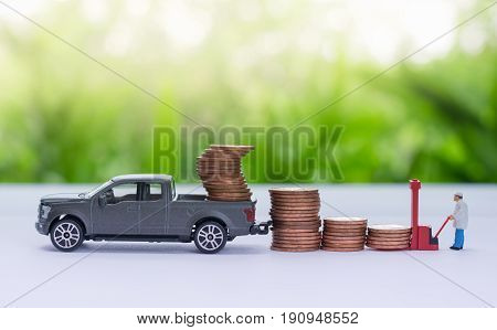 Miniature truck carrying stack of coins worker loading stack of coins using as a business concept.