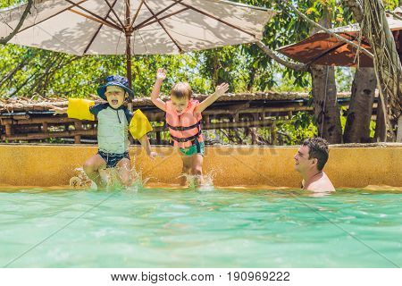 two young boys friends jumping in the pool.