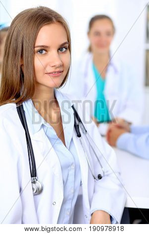 Happy doctor woman  with medical staff at the hospital sitting at the table and discussing medical history