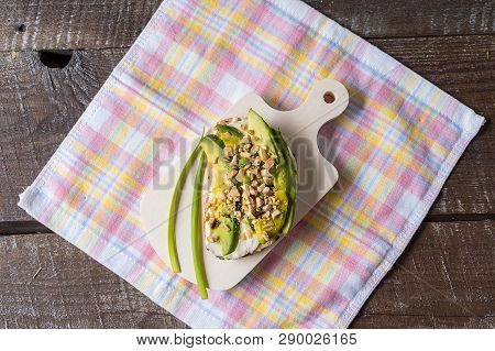 Avocado Sandwich Prepared With Cream Cheese And Nuts On A Plate, Over Napkin, Against Wooden Backgro