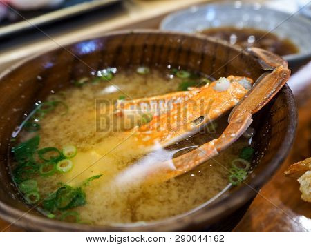 Japanese Crab Miso Soup With Visible Crab Legs And Chopped Scallion In Wooden Bowl.