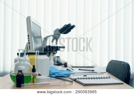 Laboratory Table With Microscope, Flasks And A Desktop Computer Above On A Window Light Background. 
