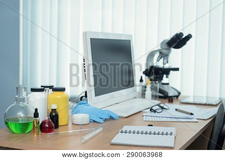 Laboratory Table With Microscope, Flasks And A Desktop Computer Above On A Window Light Background. 