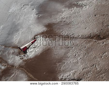 Traffic Cone Left And Partially Buried In Sand Shore Of Brisbane River, Australia.
