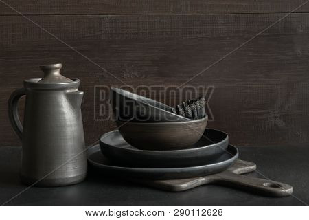 Crockery, Clayware, Dark Utensils And Stuff On Dark Tabletop. Kitchen Still Life.