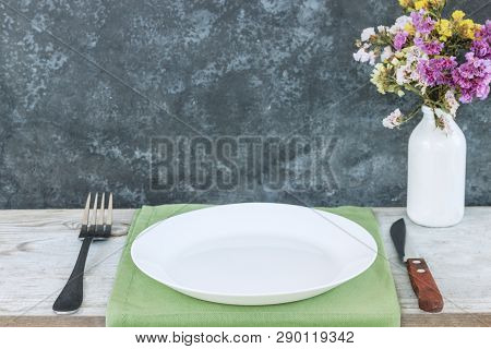 Empty Plate On Tablecloth Or Napkin On Wooden Table Over Dark Background. Table Setting.