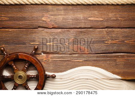 Marine Symbols - Hawser, Ship's Steering Wheel And Beach Sand On Wooden Background