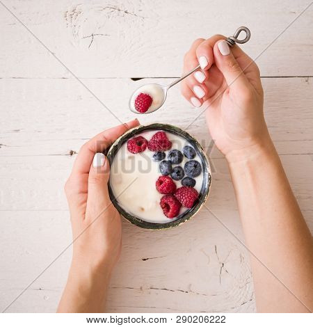 Closeup Of Young Woman Hands With A Bowl Of Yogurt. Girl Eating Organic Yogurt For Breakfast With Fr