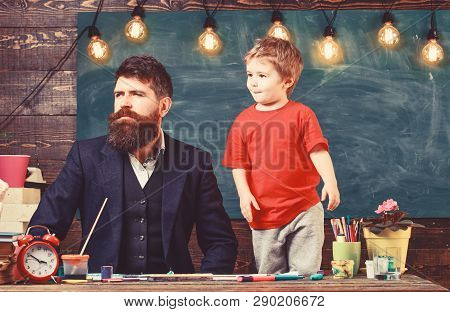 Kid With Funny Face Standing By His Father. Daddy And Son Looking Out In One Direction. Man In Smart