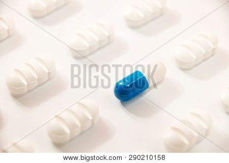 Many White Pills A Blue One On White Background