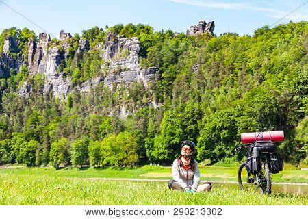 Woman Cyclist With Loaded Bicycle Having Break While Travelling. Germany, Saxon Switzerland.