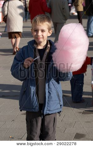 Boy eating cotton candy in the street