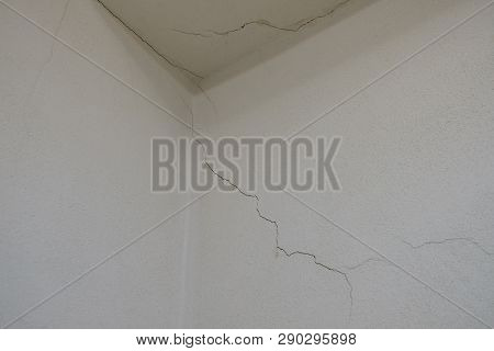 Uper Corner Of A White Room With Cracks On The Wall, Showing Signs Of A Damage Building