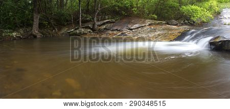 River Flowing Over Wet Rocks And The Debengeni Waterfall