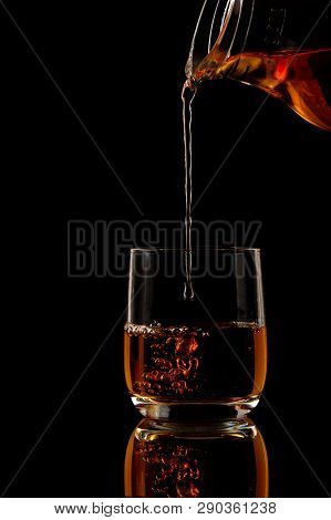 Brandy Is Poured Into A Glass On A Black Background