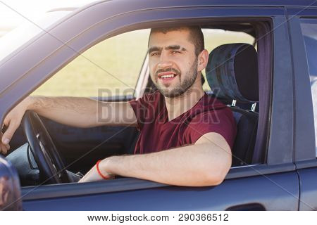 Handsome Young Dark Haired Male With Stubble Dressesd Maroon Casual T Shirt, Poses In Black Car, Loo