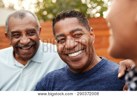 Three generations of family men laughing together, close up