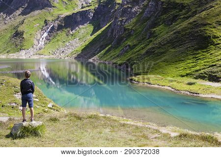 A Boy Watching The Lake Called Nassfeld Speicher In Hohe Tauern National Park In Austria