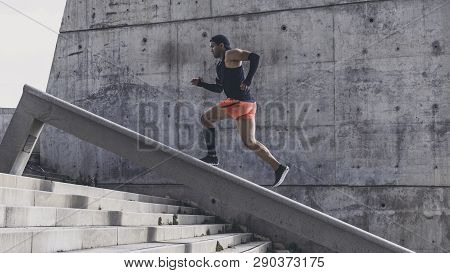 Muscular Hispanic Young Male Dark-skinned Athlete Running Up A Flight Of Stairs With Speed, Sporty Y