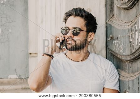 Handsome Bearded Hispanic Man Using Mobile Smartphone For Surfing Web Internet, Making Call And Look