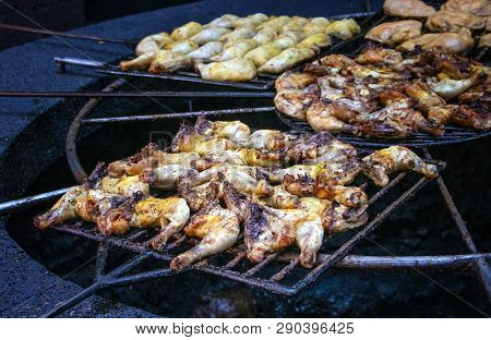 Chicken Pieces Are Baked And Roust On A Grill Above The Volcanic Stone.