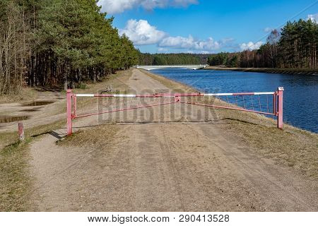 Closed Forest Path By The Water Channel. A Barrier On A Forest Duke By The River. Season Of The Spri