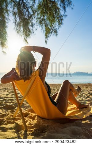 Woman enjoying her holidays on a transat at the tropical beach in Thailand - intentionnal lens flare