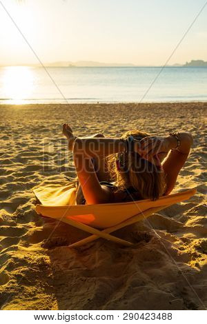 Woman enjoying her holidays on a transat at the tropical beach in Thailand at sun down