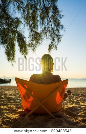 Woman enjoying her holidays on a transat at the tropical beach in Thailand - intentionnal lens flare