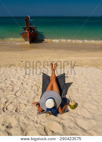 Woman with straw hat enjoying her holidays on a transat at the tropical beach in Thailand