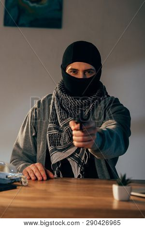 Criminal In Black Mask And Scarf Aiming Gun At Camera